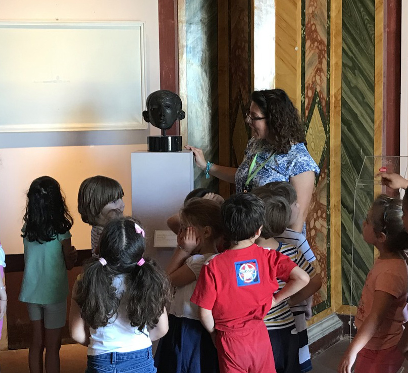 Bambini intorno ad una tela con l'insegnante durante il laboratorio